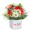 A heartfelt sense of celebration radiates from this beautifully arranged bouquet, cradled in a pristine white gift bag and designed to capture the effervescent spirit of Peckham's communities. Lush clusters of coral and soft peach carnations, each petal frilled and inviting, mingle effortlessly with bright, white daisies topped by glowing yellow-green centres-flowers as welcoming as the local faces at Peckham Square. Gentle sprays of baby's breath drift among the arrangement, their fine, cloud-like blossoms bringing a breath of innocence and effortless charm. Unfolding on the left, a few buds dusted with purple hint at stories yet to come, adding depth and intrigue reminiscent of creative evenings along Copeland Road. The bouquet's base is encircled by glossy, deep green foliage-its broad leaves forming a smooth, natural cradle, much like the leafy streets bordering Peckham Rye Park. The white ribbon handles atop the gift bag finish the presentation, offering both sophistication and practicality for delivery throughout SE15. Soft, natural lighting gleams across the scene, lifting each colour and detail while preserving a sense of freshness and sincere joy. Designed for special moments-be it a birthday, an anniversary, or the generous surprise of sending flowers to a friend-this bouquet reflects the expertise of the local florists who bring life and connection to Peckham every day.